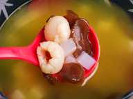 Laici dikupas, ketulan nata de coco, dan kepingan kelapa laut madu di dalam senduk merah di atas mangkuk soda berwarna kuning-jingga. Laici dikupas, ketulan nata de coco, dan kepingan kelapa laut madu di dalam senduk merah di atas mangkuk soda berwarna kuning-jingga.