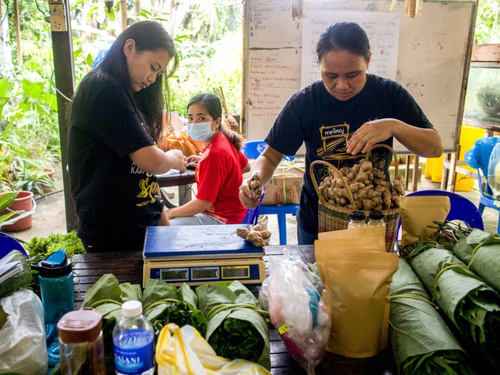 Anjelen and her team weigh and pack produce that will be sold at their community market. Photo: Natasha Sim