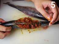 Two hands are showing the fully stuffed fish on a plastic chopping board. Two hands are showing the fully stuffed fish on a plastic chopping board.