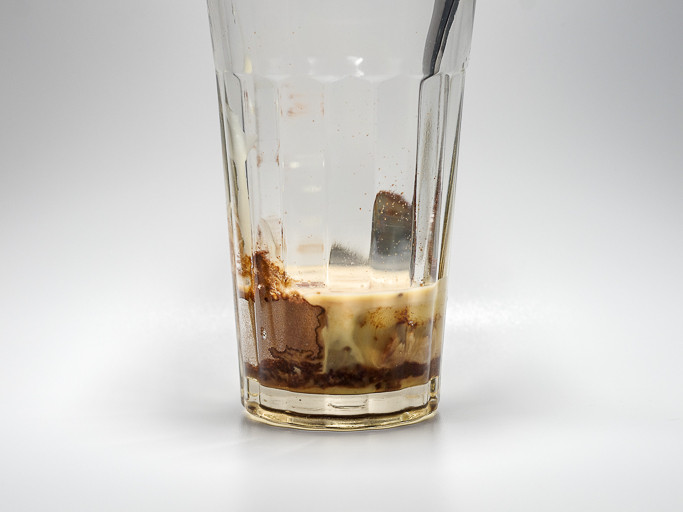 Sedikit minuman Milo dalam gelas, dicampur dengan susu