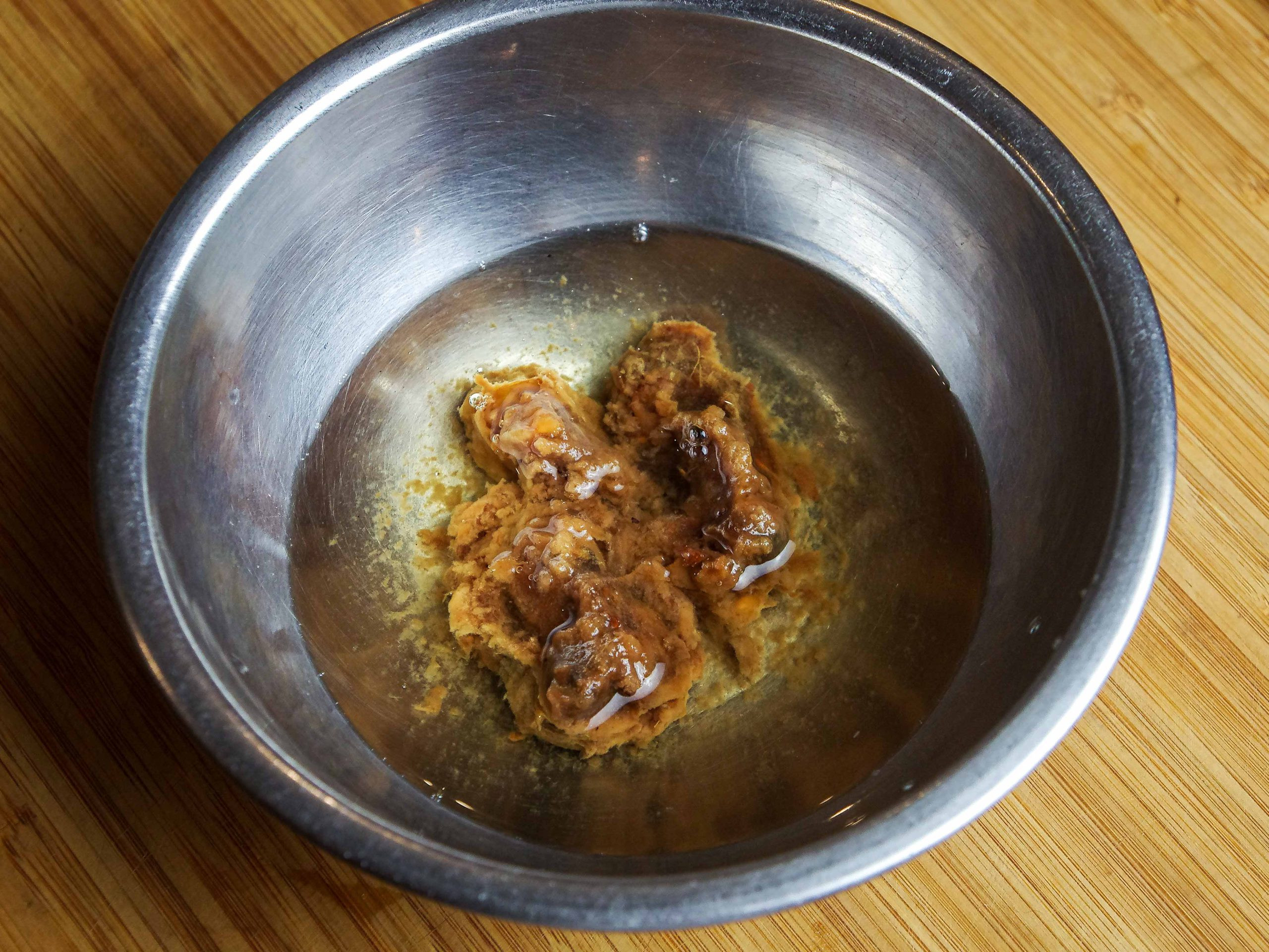 Soaked asam jawa in a metal bowl, on a wooden board,