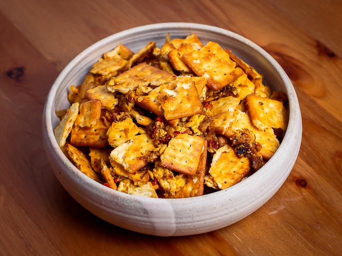 Fried cream cracker pieces in a grey bowl.